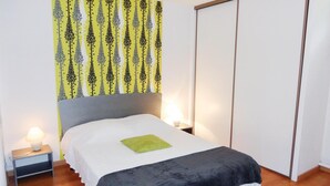 A neatly made bed with a white and black bedspread, a green pillow, and two bedside lamps.