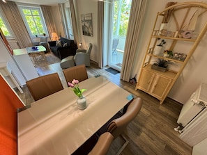 A dining area with a table, chairs, and a vase with flowers. There is a sofa and a chair in the background. - P: Villa Strandmuschel Whg. 05 - approx. 100m from the beach - Villa Strandmuschel (Sellin)