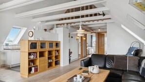 Un salon moderne avec une table basse en bois, un canapé en cuir noir et une bibliothèque intégrée.