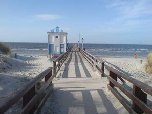 A beach boardwalk leading to a lifeguard tower with a clear view of the ocean.