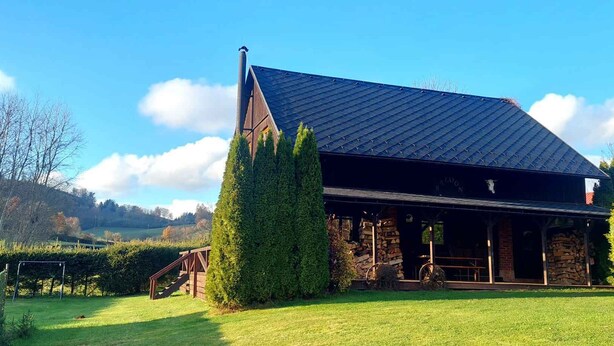 A rustic building with a sloped roof, a chimney, and a covered porch area. - Holiday home with outdoor pool and Western-style restaurant (Vlcice)