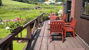 A wooden deck with outdoor seating and a large umbrella. - Holiday home with outdoor pool and Western-style restaurant (Vlcice)