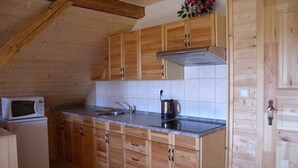 A compact kitchen with wooden cabinets, a built-in microwave, a sink, and a kettle. - Holiday home with outdoor pool and Western-style restaurant (Vlcice)