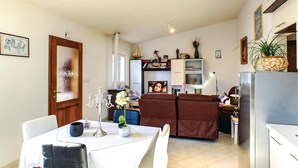 A compact living space with a dining area, a sofa, a TV, and a kitchen area.