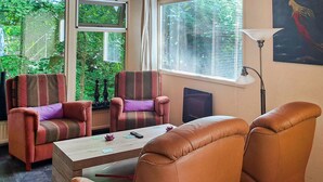 Ein Wohnzimmer mit gestreiften Sesseln, einem Couchtisch und einer Stehlampe.