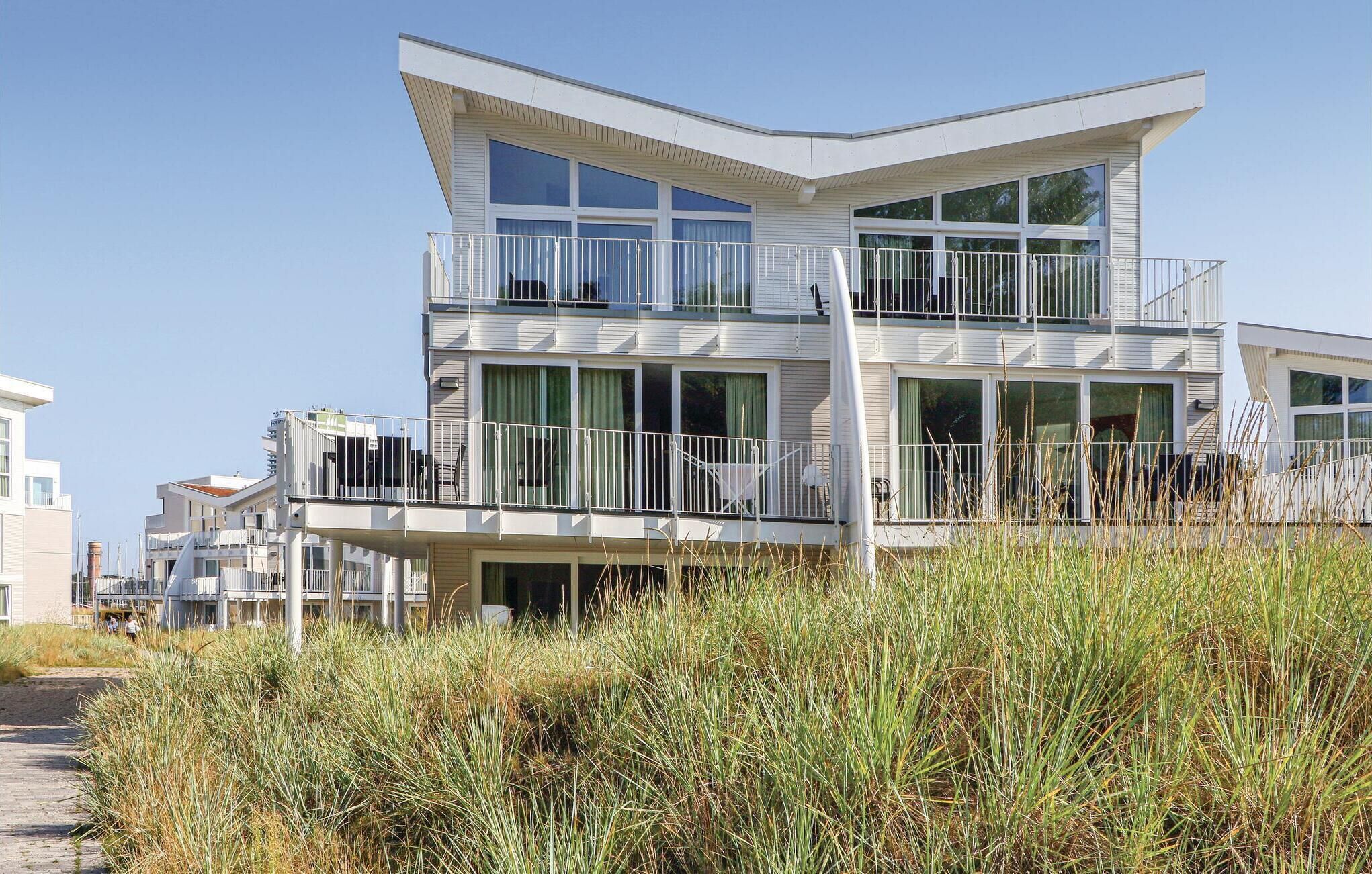 A modern multi-story building with balconies, large windows, and a flat roof.