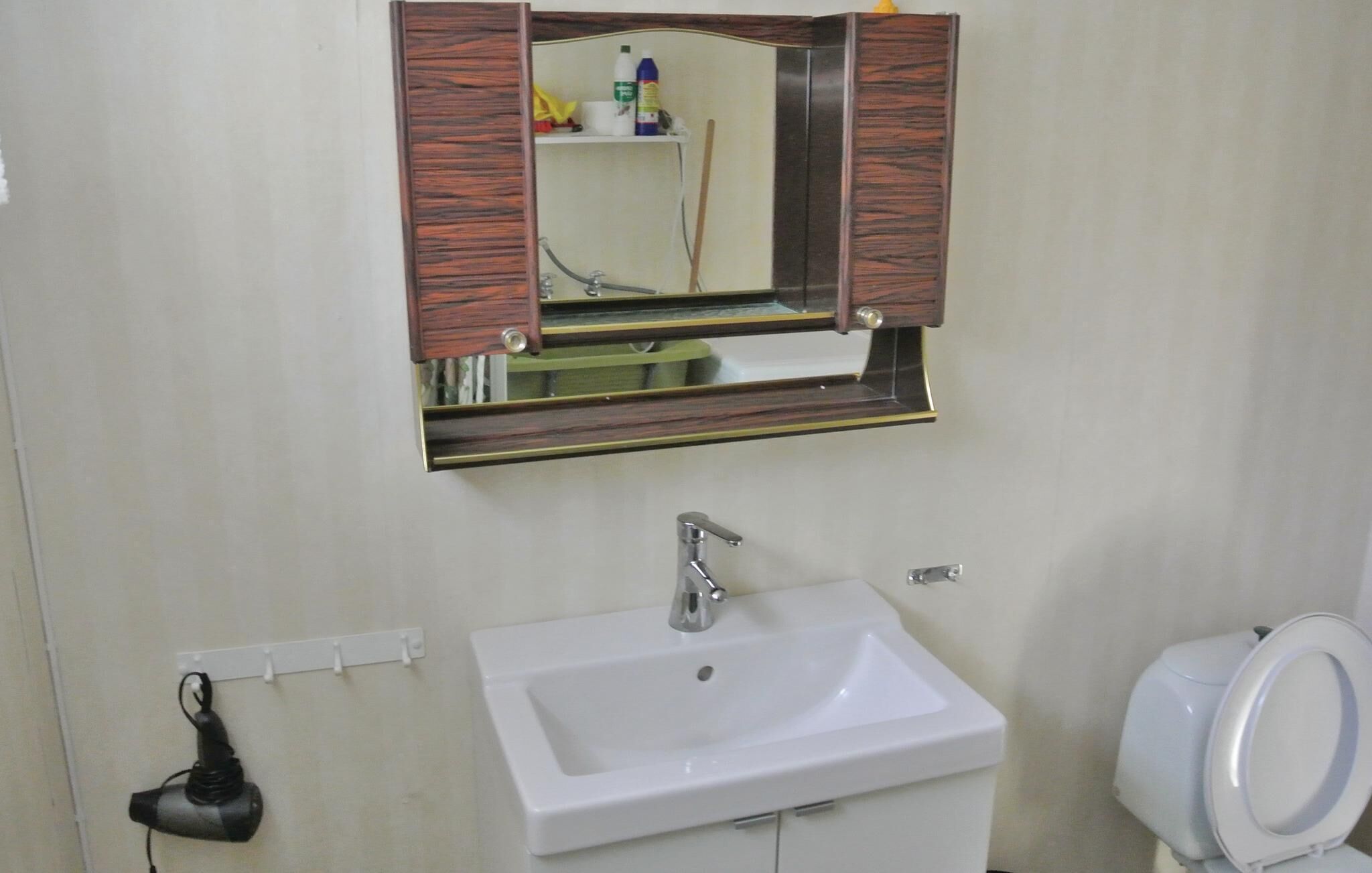 A bathroom with a white sink, a mirror with a wooden frame, and a toilet.