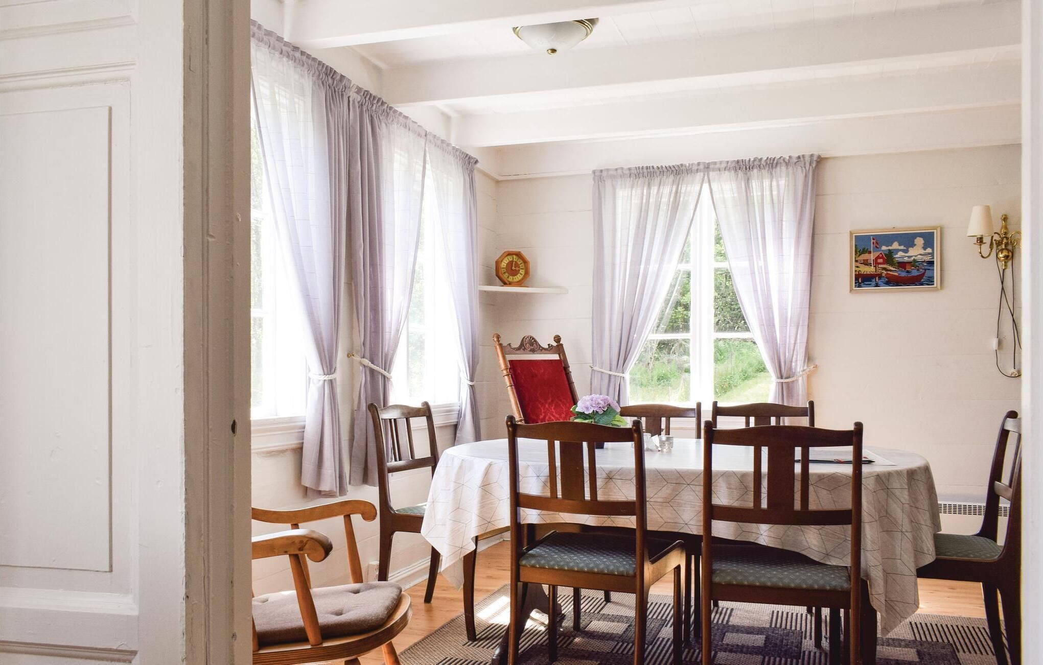 A dining room with a table set for four, surrounded by wooden chairs with cushioned seats.