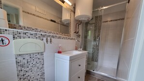 Une salle de bain avec des toilettes, un lavabo et une douche.