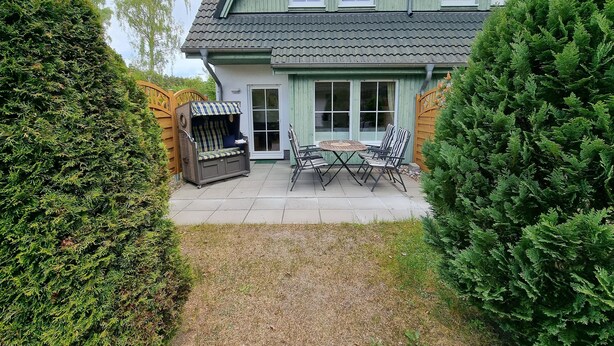 Une maison dotée d’un patio comprenant une table et des chaises, un espace salon couvert et une grande fenêtre.