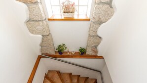 A staircase with wooden steps and a metal handrail, leading to a landing with a stone wall and a window with a plant on the sill. - Gorgeous home in Barci (Barci)