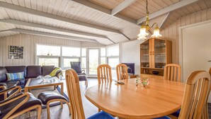 Un salón espacioso con una mesa de comedor de madera rodeada de sillas, un sofá de cuero y un televisor.