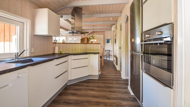 Una cocina moderna con paneles de madera, electrodomésticos de acero inoxidable y una isla central.