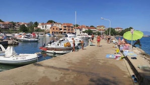 Ein Yachthafen mit vertäuten Booten, einem Sandweg und Gebäuden im Hintergrund.