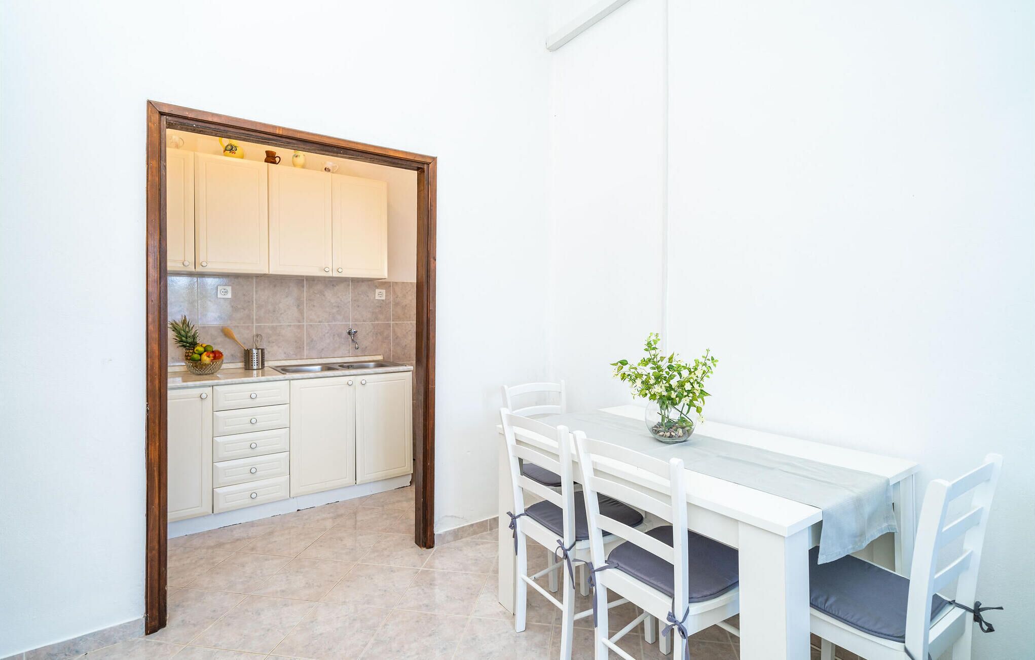 A compact kitchen with white cabinets, a sink, and a dining area with a table and chairs.