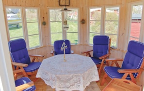 A wooden-paneled room with a round table covered in lace, surrounded by blue chairs. - Awesome home in Sölvesborg with kitchen (Sölvesborg)
