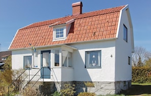 A two-story house with a red-tiled roof, white exterior walls, and a small porch with a blue door. - Awesome home in Sölvesborg with kitchen (Sölvesborg)