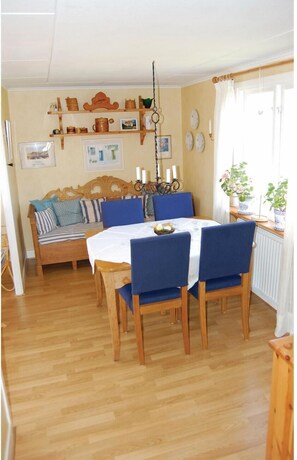 A cozy room with a wooden dining table, blue chairs, a wooden sofa, and a hanging light fixture. - Awesome home in Sölvesborg with kitchen (Sölvesborg)