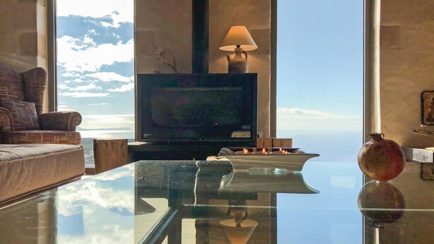 Un salon moderne doté d’un grand téléviseur, d’une table basse en verre et offrant une vue sur l’océan.