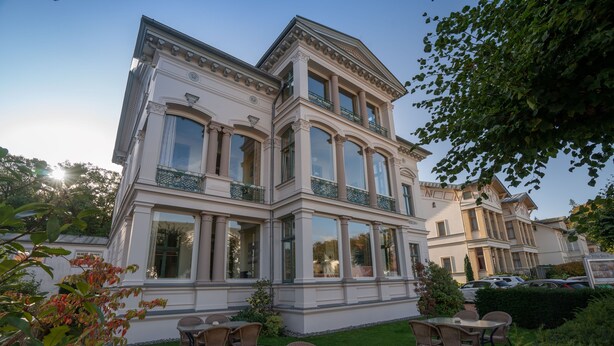 A large, multi-story building with a classical architectural style, featuring large windows and a balcony.