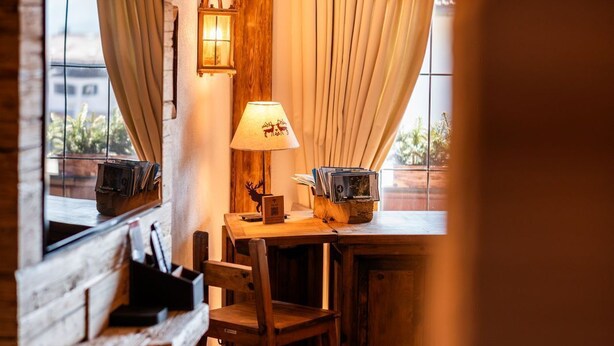 Une pièce confortable avec un bureau en bois, une chaise, une lampe et une fenêtre avec des rideaux.