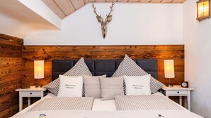 Une chambre à coucher avec une tête de lit en bois, une literie à carreaux et une tête de cerf accrochée au mur.