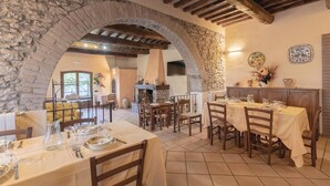 A dining area with stone arches, wooden beams, and tiled flooring. Tables are set with plates, glasses, and cutlery. - Amazing home in Magione (PG) (Magione (PG))