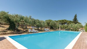 A rectangular swimming pool with a tiled edge, surrounded by lounge chairs and a stone wall. - Amazing home in Magione (PG) (Magione (PG))