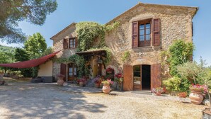 A stone house with a gravel driveway, wooden shutters, and potted flowers. - Amazing home in Magione (PG) (Magione (PG))
