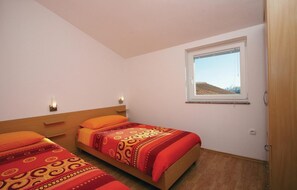 Ein Schlafzimmer mit zwei Betten, einem Fenster mit Blick und einer Holzbalkendecke.