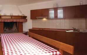 Eine Küche mit Holzausstattung, Fliesenrückwand, eingebautem Backofen und kariertem Tischläufer.