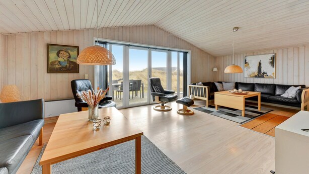 Uma sala de estar ampla com teto alto, uma grande porta de correr de vidro que dá para área externa e design de interiores moderno.