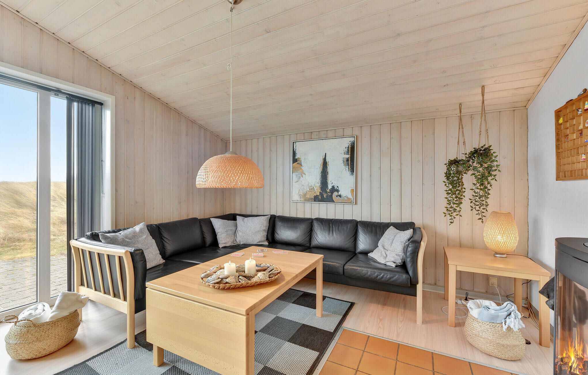 A modern living room with a black leather sofa, a wooden coffee table, and a fireplace.