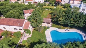 Vue aérienne d’une propriété dotée d’une piscine, de bâtiments en pierre et d’un environnement verdoyant.