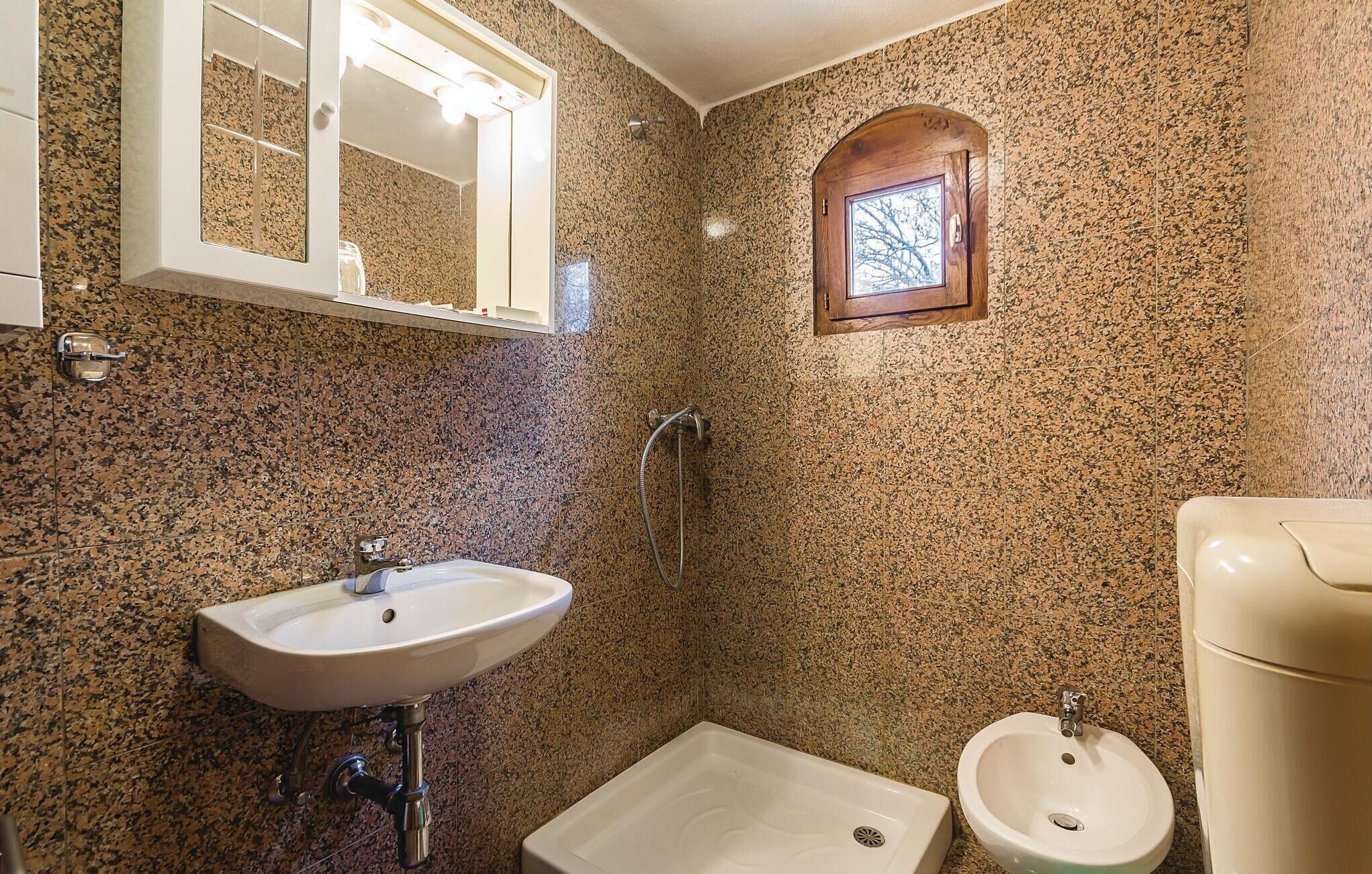 Ein Badezimmer mit einer Granitwand, einem Standwaschbecken, einer Dusche und einer Toilette.