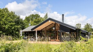 Ein modernes Haus mit großer Glasfassade, einem markanten Schornstein und einer geräumigen Veranda.