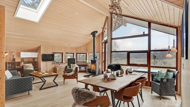 Eine geräumige Hütte mit hohen Decken, großen Fenstern, einem zentralen Kamin und einer gemütlichen Sitzecke.
