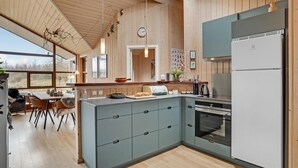 Eine moderne Küche mit Einbauofen, Kühlschrank und Essbereich mit Blick.