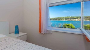 Una camera da letto con vista su un corpo d'acqua e vegetazione.