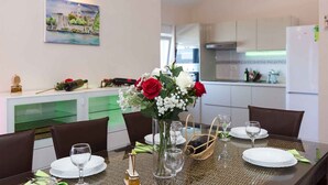 Un'area pranzo con un tavolo apparecchiato per quattro persone, un vaso con fiori e un quadro appeso al muro.
