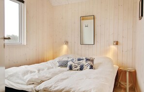 A bedroom with a bed, a window, a mirror, and wall-mounted lights.
