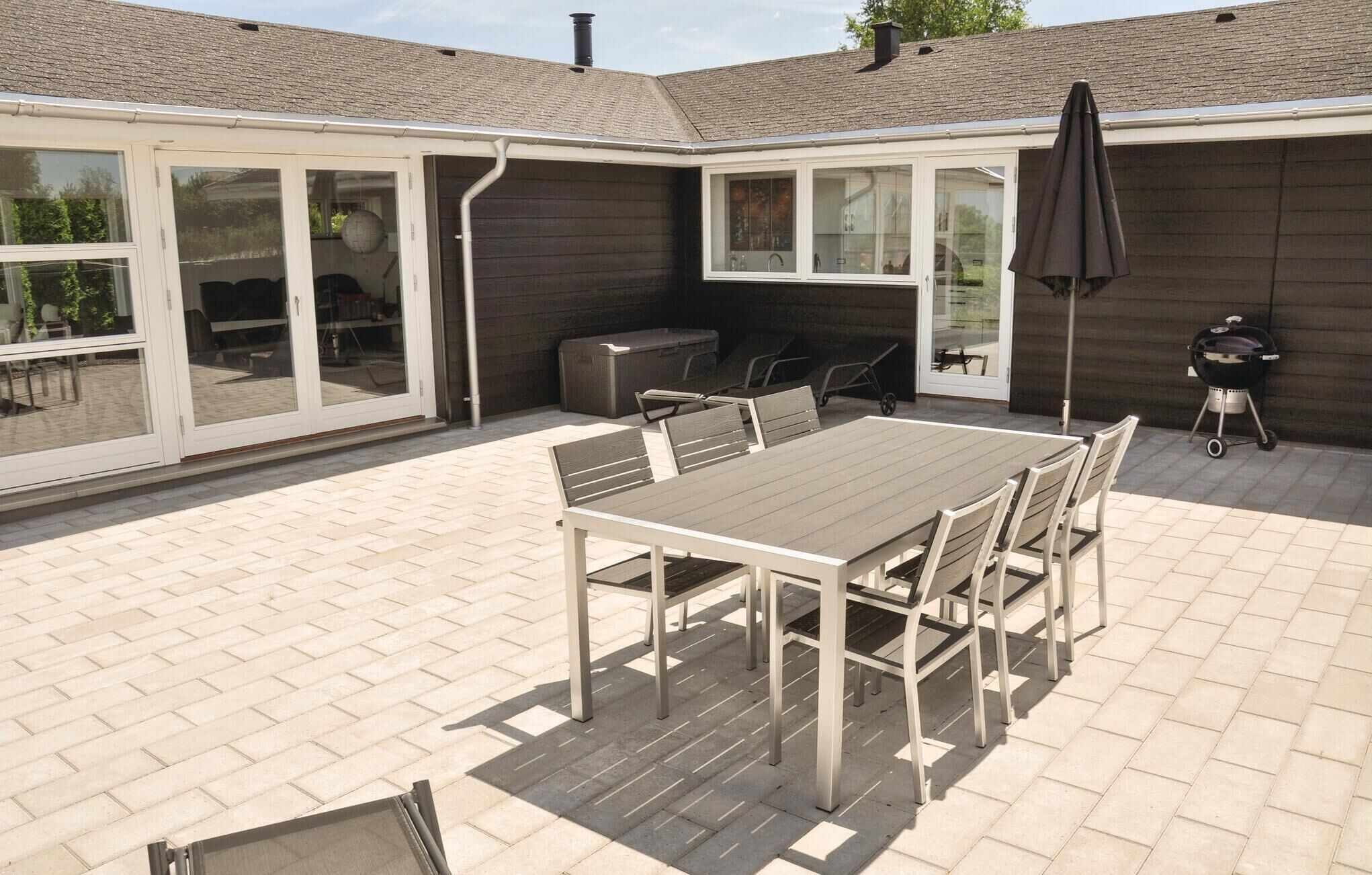 Un patio con tavolo e sedie, un barbecue e una zona relax coperta.