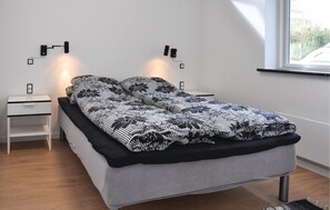 A modern bedroom with a bed, two nightstands, and wall-mounted lamps.