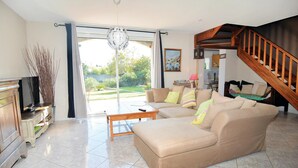 A spacious living room with a beige sofa, a wooden coffee table, and a television on a wooden cabinet. - Nice home in Eyguieres with WiFi (Eyguieres)