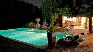 A swimming pool with lounge chairs and potted plants, surrounded by a patio area with tables and chairs. - Nice home in Eyguieres with WiFi (Eyguieres)