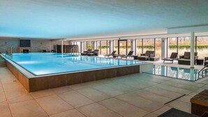 Ein großes Hallenbad mit Liegestühlen und einem Kamin.