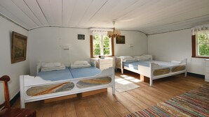 Ett rum med två sängar, ett fönster, en takfläkt och en tavla på väggen.