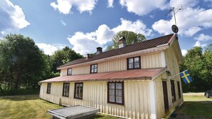 Ett tvåvåningshus byggt av trä, med ett rött tegeltak, en liten veranda och en flagga.