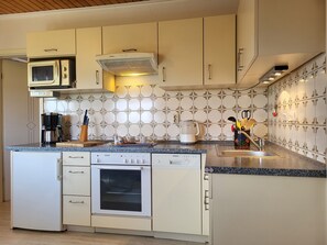 A kitchen with a microwave, coffee maker, and oven.