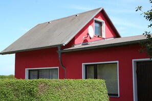 A red building with a sloped roof, two windows, and a satellite dish.